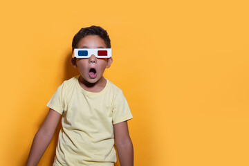 Amazed child with 3D glasses on a yellow background