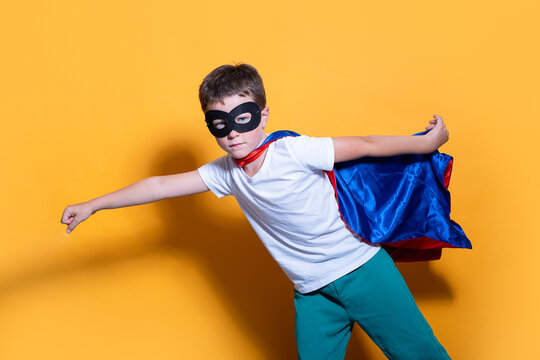Young superhero in pose on vibrant yellow background