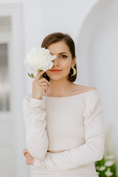 Elegant girl model with flower in studio with white wall