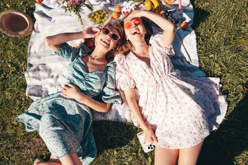 Two young beautiful smiling hipster female in summer sundress and hats. Carefree women making...