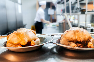 Grilled chicken menu prepared in the kitchen of a restaurant with female chef and staff working in the background