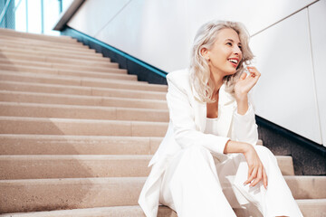 Young beautiful blond woman wearing nice trendy white suit jacket. Smiling model posing in the...