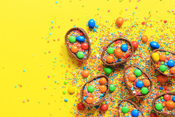 Chocolate eggs with candies and sugar colored sprinkles on a blue background, top view. Easter...
