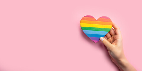 Abstract background. LGBTQ concept with a hand holding a rainbow paper heart represents equal love...