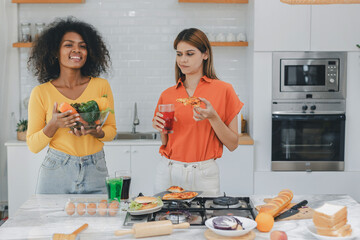 Two women choosing between vegetable and sausage, organic food vs gmo products. Young woman making...