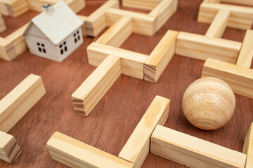 Miniature white house in a wooden maze,  wooden maze made with wood blocks and a wood sphere ...