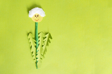 Hand made paper cut dandelion on green cardboard background, spring time concept with copy space