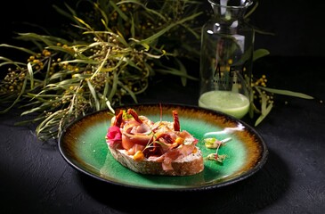 Sumptuous open-faced sandwich, adorned with prosciutto and edible flowers on artisan bread in the...