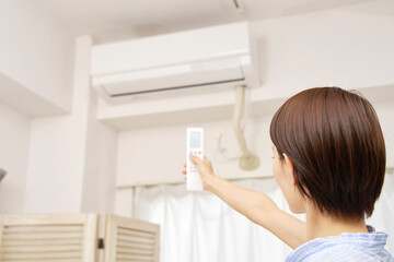 エアコンのリモコンを使う女性