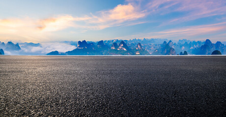 Asphalt road and karst mountain with sky clouds at sunrise