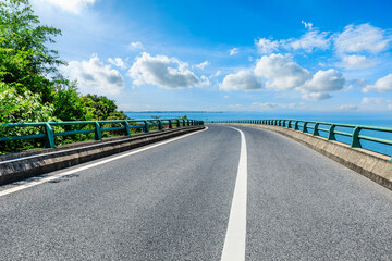 Asphalt highway road and green tree landscape by the lake