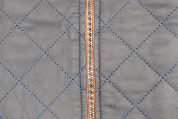 Macro shot of zipper on black leather texture background with stitching. Close-up of black leather material
