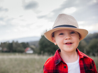 boy of two years old in a hat and red shirt in a field