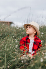 boy of two years old in a hat and red shirt in a field