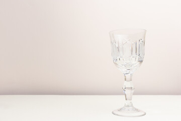 Vintage crystal glass in front of beige background. Place for your design.