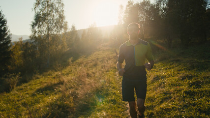 Bearded healthy Caucasian millennial male man guy runner sportswear running outdoors sunny mountain...