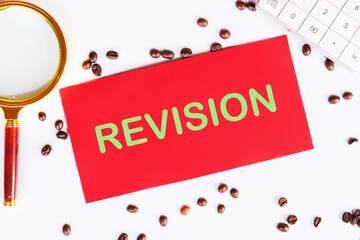 Business concept. REVISION word on red paper on a white background with coffee beans and a...