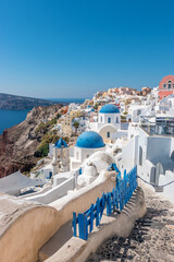 View of Oia town with traditional and famous houses and churches with blue domes over the Caldera on Santorini island. Greece.