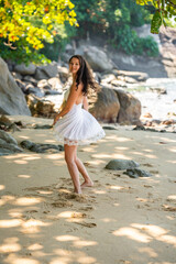 Stylish attractive young woman wearing in white dress having fun on on seashore in the shade of trees and palms, freedom and happiness