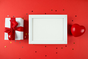 white wooden photo frame gift box and red heart on red background. Copy space. place for text.