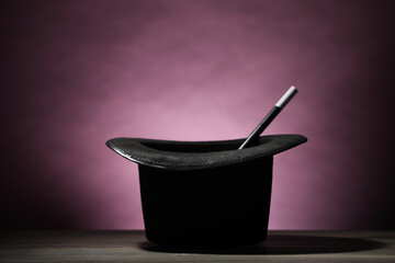 Magician's hat and wand on wooden table against dark background