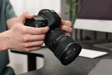 Photographer holding camera at dark table, closeup
