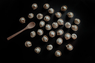 Dumplings on black background with wooden spoon
