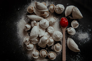 Dumplings on black background with wooden spoon with red ketchup sause