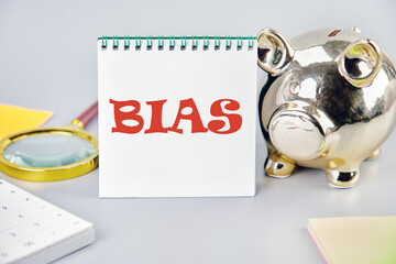 Concept of facts and biases. A word BIAS on a vertically standing notebook near a piggy bank, a...