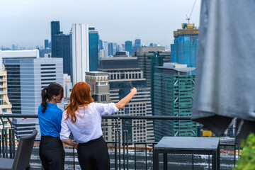 Rear view office women standing at balcony looking at downtown cityscape