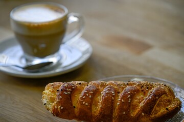 Isolated high resolution close up image of a single small hala bread with a cup of coffee in the...