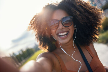 Happy young woman having video conversation with smartphone while staying in the street.