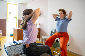 Woman stretching in a clinic with therapist assisting