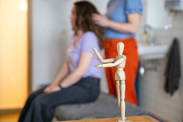 Wooden mannequin in focus with blurry hairstyling session in background