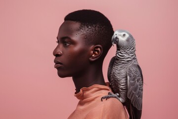 grey jaco pet parrot sitting on a man’s shoulder, portrait of male with domestic african parakeet on plain background - Powered by Adobe