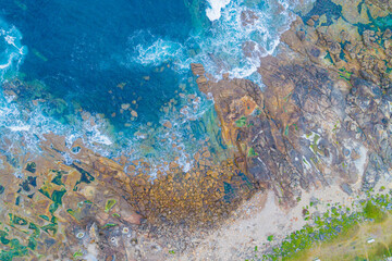 directly above drone view of sea waves on a rocky shore