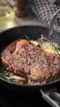 A chef cooks a beef steak on a pan in the kitchen, close-up. Process of making delicious steak.