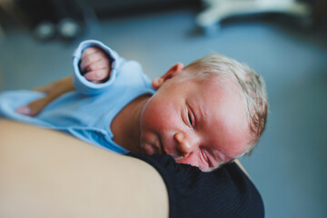 A close-up of a newborn baby lying on his mother's arms.