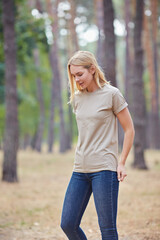 Obraz premium Attractive blue eyed blonde woman walk on the city park. Girl wear beige t-shirt, pink bag and look happy and smiles.