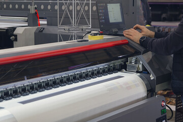 A man adjusts the printing process on a large format printing machine