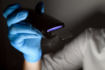 Blue device in hand of specialist in a beauty field in a blue rubber gloves