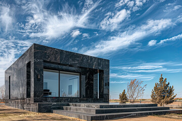 Fototapeta na wymiar A chic onyx house, standing boldly within a simplified suburban landscape, under the expansive blue sky.