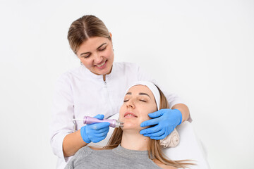 Doctor in overalls and blue rubber gloves makes a procedure on face of a girl in a clinic of beauty