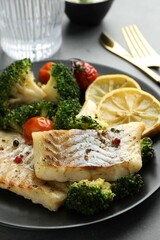 Tasty cod cooked with vegetables served on grey table, closeup