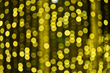 Abstract bokeh effect of the gold, yellow lights on black background. City street light decorations. Rows of LED gold colored light spots with black background. 