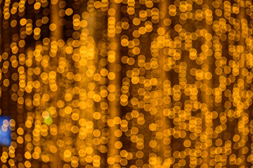 Abstract bokeh effect of the gold, yellow lights on black background. City street light decorations. Rows of LED gold colored light spots with black background. 