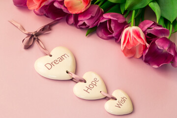 greeting card, banner, pink and purple tulips on a pink background and ceramic hearts with the inscription Dream, Hope, Wish