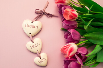 greeting card, banner, pink and purple tulips on a pink background and ceramic hearts with the inscription Dream, Hope, Wish