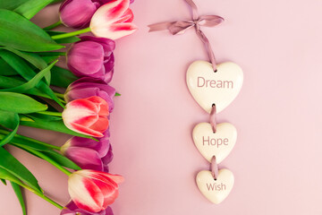 greeting card, banner, pink and purple tulips on a pink background and ceramic hearts with the inscription Dream, Hope, Wish