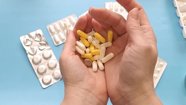 Female hands holding a handful of pills close-up.